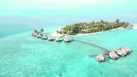 Resortsziget fehér homokos parttal és víz feletti villákkal a türkiz lagúnában